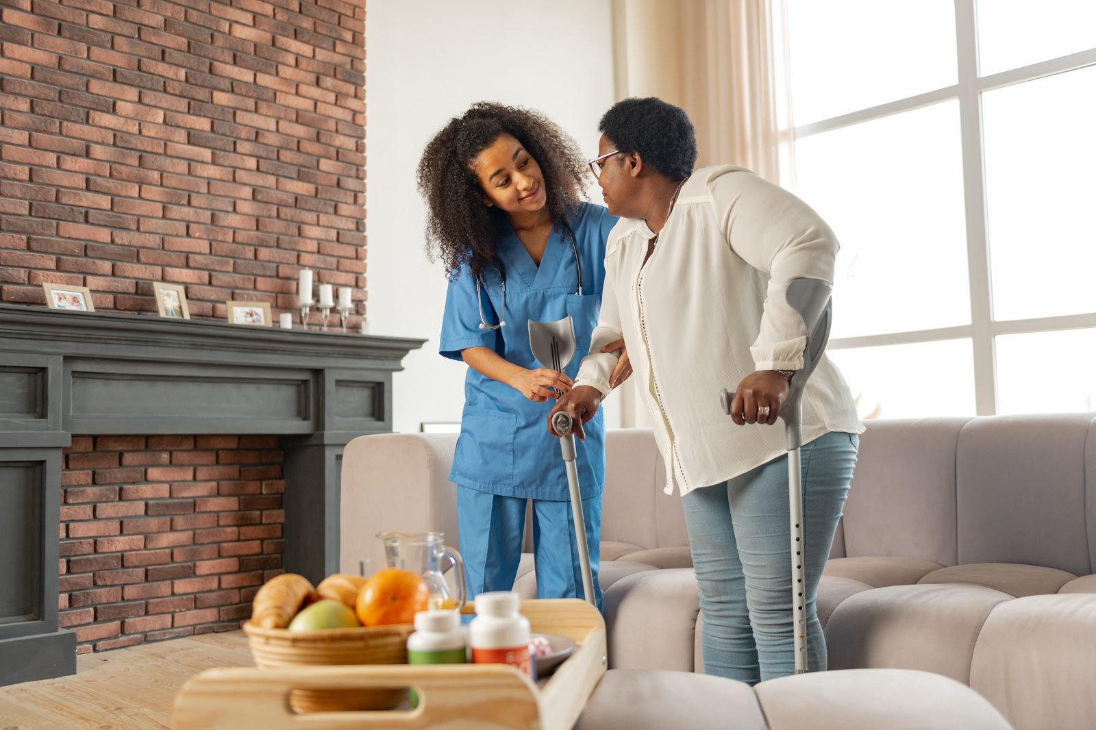 A caregiver helping a client stand with crutches at home