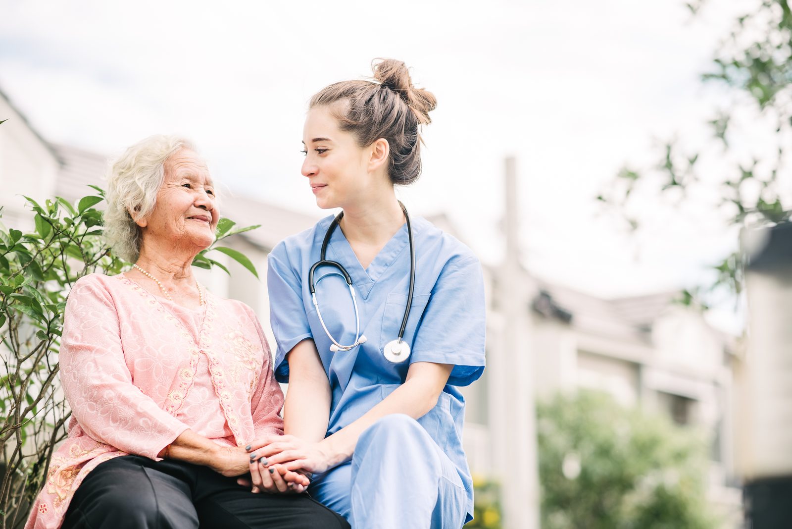 A caregiver holding hands with a senior woman outdoors