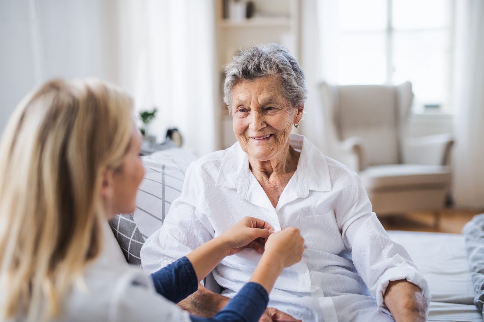 A caregiver helping a senior woman get dressed